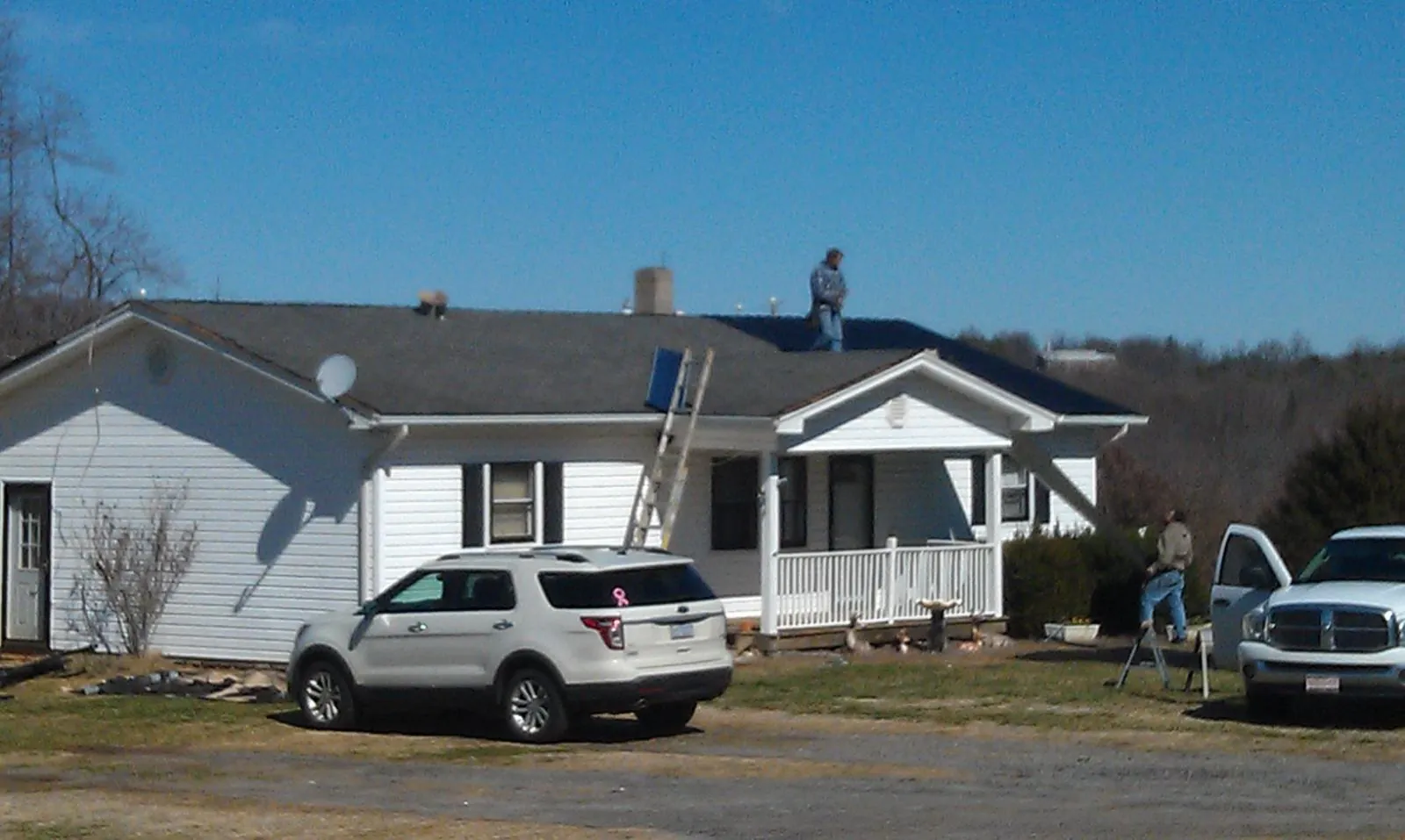 Roofers stripping shingles from a white ranch house roof in Dunnellon