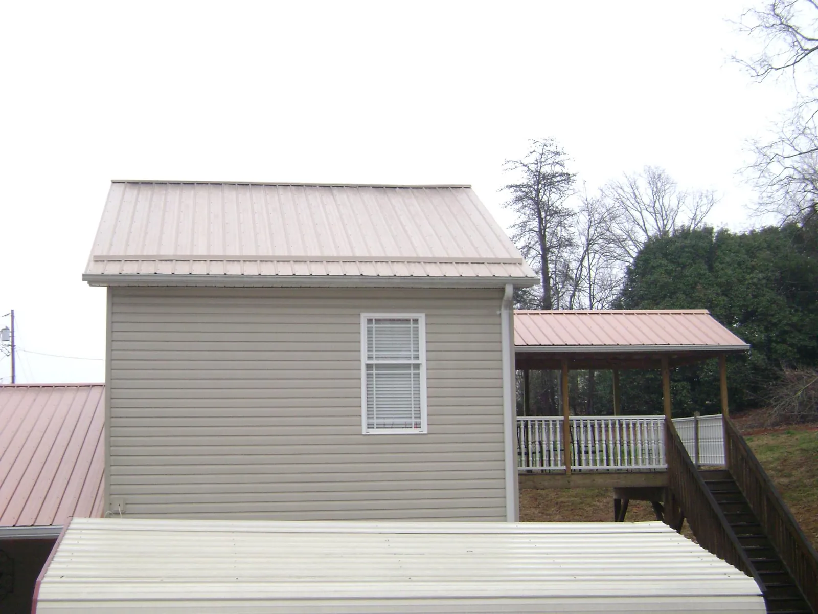 Tan metal roofs on a two story addition and attached porch, from a Roof Replacement job in Dunnellon